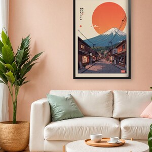 Pode incluir: Uma impress&atilde;o emoldurada de uma cena de rua japonesa com o Monte Fuji ao fundo. O sol se p&otilde;e atr&aacute;s da montanha, lan&ccedil;ando um brilho quente sobre a cena. O texto na impress&atilde;o diz "峰と雲に抱かれた街".