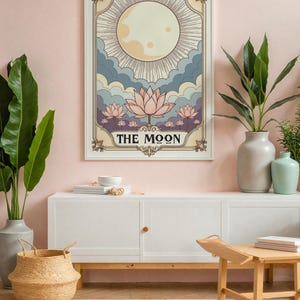 May include: A vintage-style tarot card print featuring the Moon card. The card depicts a full moon with rays of light, clouds, and lotus flowers. The text "THE MOON" is written in a decorative font at the bottom of the card.