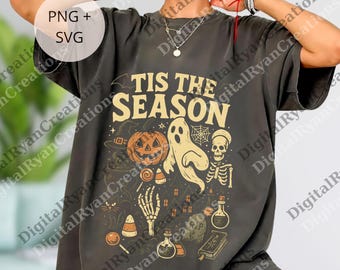 May include: Dark gray t-shirt with a Halloween-themed graphic. The design includes a jack-o'-lantern, ghost, skeleton, and the text "TIS THE SEASON" in a vintage style. Additional elements include candy corn and potion bottles.