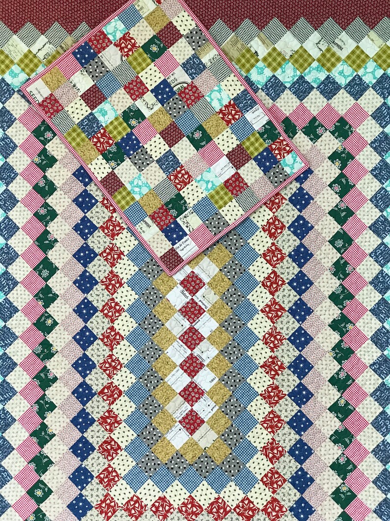 May include: A patchwork quilt with a diamond pattern in various colors, including red, blue, green, and pink. A smaller quilt with a similar pattern is placed on top. The quilts are made of small, square fabric pieces.