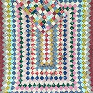 May include: A patchwork quilt and pillow set with a diamond pattern. The quilt features squares of various colors, including red, blue, pink, and green. The border is a solid maroon color. The pillow is a smaller version of the quilt.