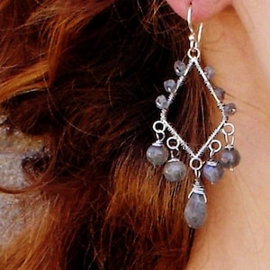 May include: Silver dangle earrings with a geometric design and gray gemstone accents.