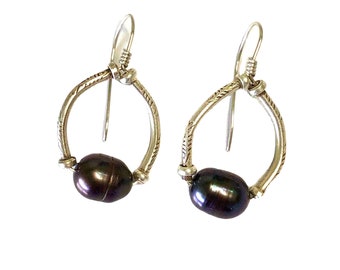 May include: A pair of silver hoop earrings with a black pearl dangling from each hoop.