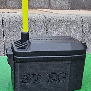 以下が含まれることがあります： 黄色いアンテナと側面に「3D RC」と印刷された黒いプラスチック製のバッテリーボックスです。