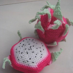 May include: Two crocheted dragon fruit toys. One is pink with green leaves and the other is pink and white with a white center and black seeds.