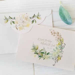 Puede incluir: Un sobre blanco con un borde festoneado y un diseño floral de acuarela. El sobre está abierto para revelar una tarjeta con una corona floral de acuarela y el texto "A Sweet Friendship Refreshes the Soul" con la referencia bíblica "Prov 27:9".