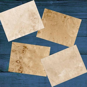 Puede incluir: Cuatro hojas de papel envejecido, de color blanco roto, con manchas marrones y pliegues. El papel est&aacute; dispuesto sobre una superficie de madera azul.