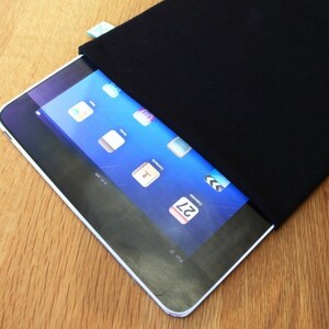 May include: A black tablet case with a zipper closure. The case is made of a soft, durable material and is designed to protect your tablet from scratches and bumps. The case is shown with a tablet inside, which has a blue screen with icons and a calendar date.
