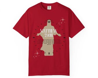 May include: A red t-shirt with a graphic of a figure with outstretched arms, the text "MATTHEW 24:36" above and a quote below. The design includes star-like accents. The shirt is made of a soft material.