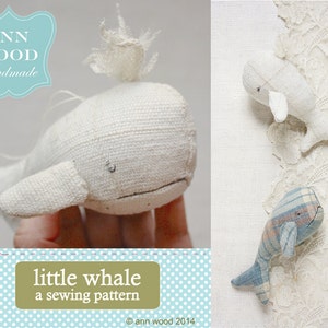 Könnte beinhalten: Ein Nähmuster für einen kleinen Wal, mit einem weißen Wal, einem blau-weißen Wal und einem weißen Wal mit einem weißen Büschel oben. Das Muster heißt "little whale a sewing pattern" und ist von Ann Wood.