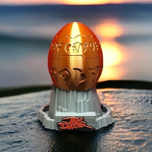 May include: A gold egg with intricate designs sits on a gray, rocky base with the words "Jak & Daxter" printed on the front.