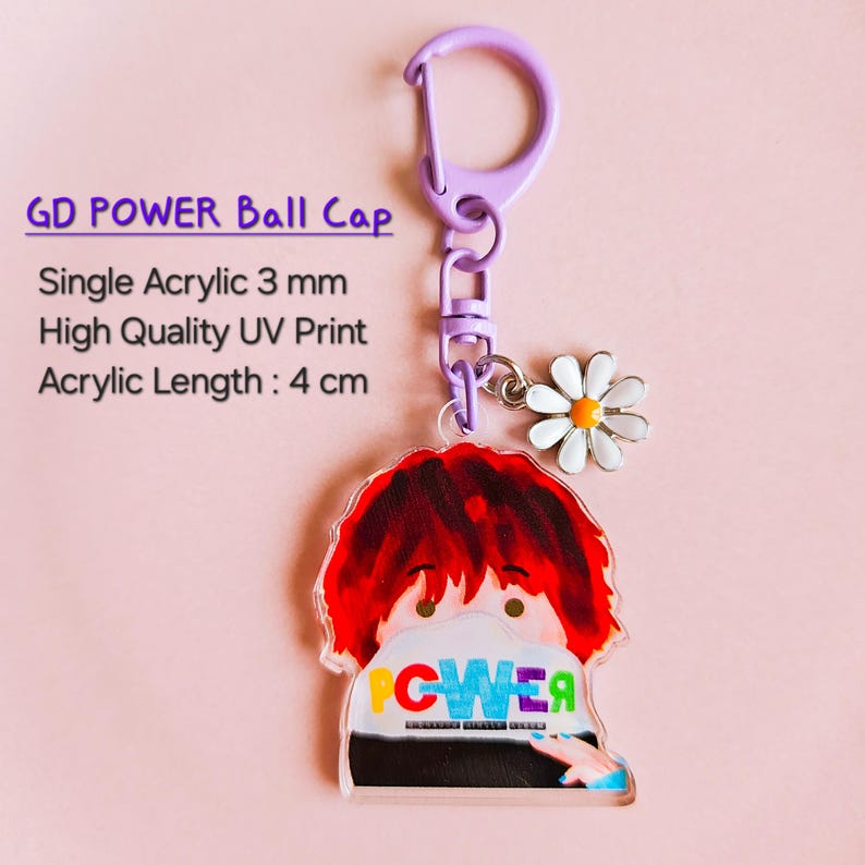 May include: A clear acrylic keychain with a cartoon graphic and the word "POWER" in blue and green. The keychain has a purple clasp and a daisy charm. The acrylic length is 4 cm.