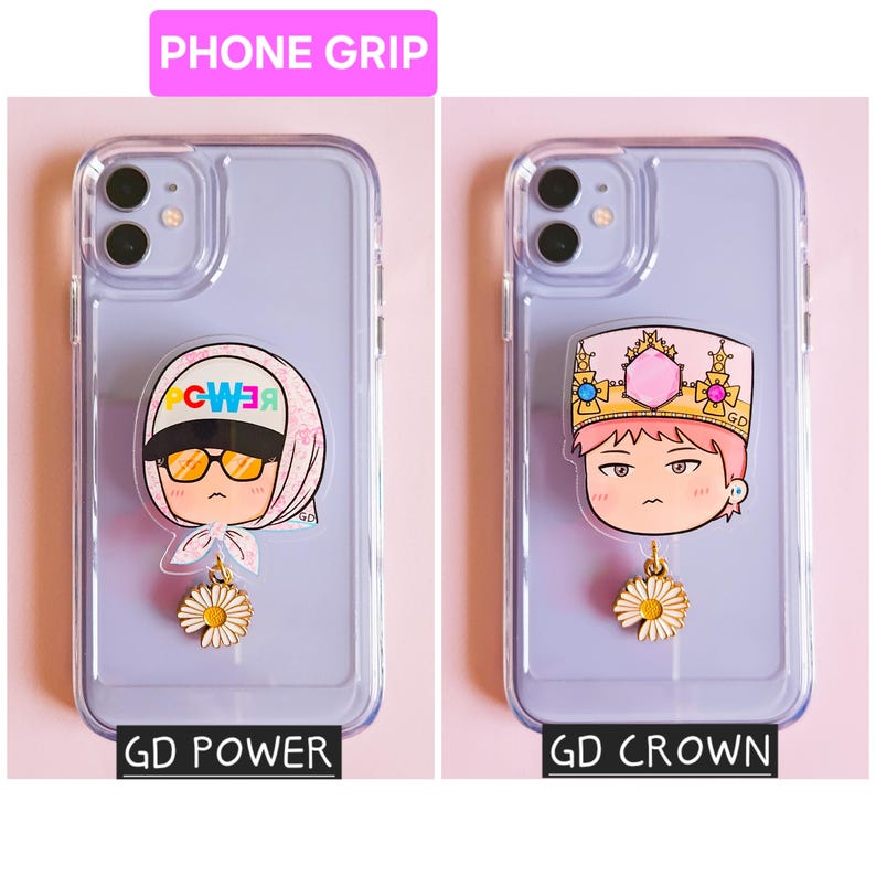 May include: Two phone cases with attached phone grips. One grip features a cartoon character wearing sunglasses and a headscarf, the other a cartoon character wearing a crown. Both have a daisy charm and text that reads "GD POWER" and "GD CROWN".