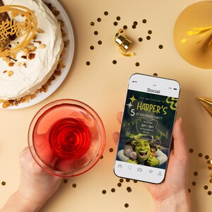 K&ouml;nnte beinhalten: Ein Smartphone, auf dem eine Social-Media-Einladung zu einer 5. Geburtstagsfeier angezeigt wird. Die Einladung zeigt einen gr&uuml;nen Oger und einen Esel aus dem Film Shrek. Der Text auf der Einladung lautet "You are invited to Harper's 5th Birthday Party".