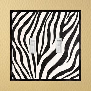 May include: A black and white zebra print light switch cover with two toggle switches.