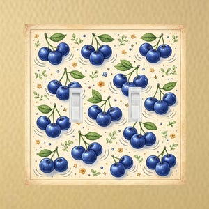 May include: A double light switch cover featuring a repeating pattern of blue cherries with green leaves and small yellow flowers on a cream background. The light switches are white.