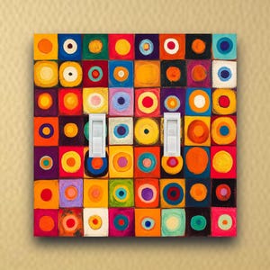 May include: A colorful light switch cover with a vibrant abstract design. The cover features a grid of squares in various colors, each with a circle in the center. Two white light switches are in the center of the cover.
