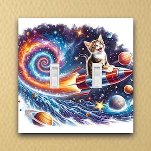 May include: A light switch cover featuring a cartoon cat riding a rocket through a colorful galaxy with stars and planets. The cat is wearing a red collar and has a white chest.