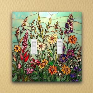 May include: A decorative light switch cover featuring a stained-glass design of a colorful wildflower meadow. The cover has two white toggle switches and is set against a light blue background. The flowers include red, yellow, orange, and purple blooms.