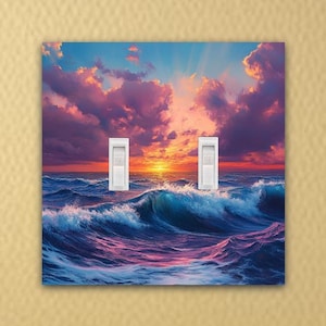 May include: A double light switch cover with a colorful sunset over the ocean. The sky is a mix of pink, purple, and orange with white clouds. The ocean is a deep blue with white waves crashing.