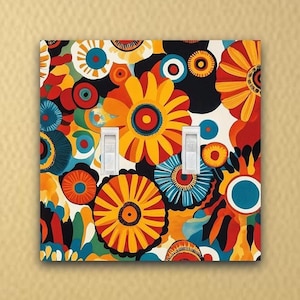 May include: A light switch cover with a colorful floral pattern featuring yellow, orange, red, blue, and green flowers. The switch cover has two white toggle switches.