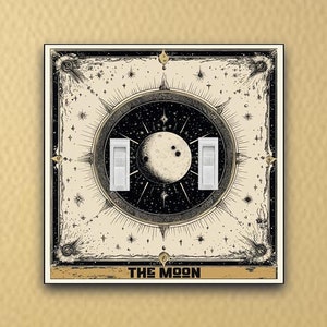 May include: A light switch cover featuring a vintage illustration of the moon with stars and the text "THE MOON".