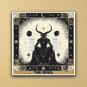 May include: A black and gold light switch cover with a tarot card design featuring a horned figure sitting on a throne with the text "THE DEVIL" at the bottom.