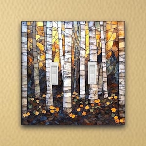 May include: A decorative light switch cover featuring a stained glass design of birch trees in a forest. The artwork includes white, brown, yellow, and orange colors. The cover has two white light switches.