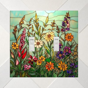 May include: A double light switch cover featuring a stained glass design of colorful wildflowers including yellow, orange, red, purple, and pink blossoms against a light blue background with dark leaded lines throughout the floral pattern.