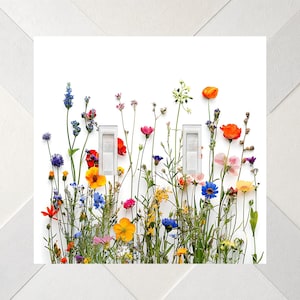 May include: A double light switch wall plate featuring a white background printed with a colorful array of wildflowers including orange, blue, pink, and yellow blossoms on thin green stems. Two rectangular white toggle switches are centered.