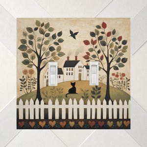 May include: A square double light switch cover featuring a painted scene of a white house with chimneys, a black cat sitting on a hill, two trees, and a white picket fence. The bottom border displays a row of small, colorful painted hearts.