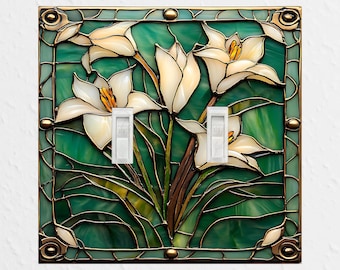 May include: A square double light switch cover plate featuring a stained glass design of white lily flowers with yellow centers against a variegated green background, framed by a dark metal border with decorative corner accents.
