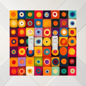 May include: A double light switch wall plate featuring a grid of colorful squares, each containing a painted circle in contrasting hues of red, orange, yellow, blue, green, and purple. The two white toggle switches are positioned vertically.