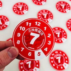 May include: A red and white circular sticker with the text "点検整備" and the number "7" in the center. The sticker has numbers 1 through 12 around the edge.