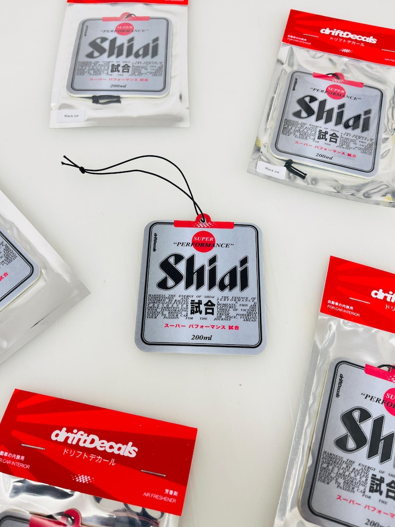 May include: A silver car air freshener with a red and white label that says "Super Performance Shiai 試合" and "200ml". The air freshener is hanging from a black string.