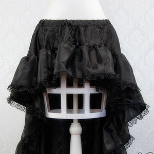 May include: Black satin skirt with a layered ruffle design and black lace trim. The skirt is high-low, with a shorter front and a longer back.