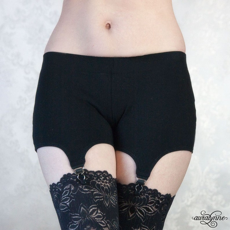 May include: Black cotton shorts with six adjustable straps. The straps are attached to the shorts with metal rings. The shorts are designed to be worn with suspenders.