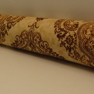 May include: A brown and beige doorstop with a paisley pattern. The doorstop is made of fabric and is filled with stuffing.