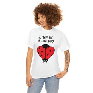 May include: White t-shirt with a red ladybug graphic and the text "Bitten by a Lovebug."