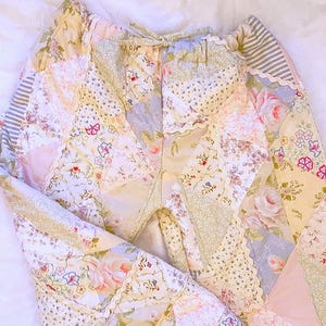 Könnte beinhalten: Eine weiße Keramik-Tasse mit schwarzem Henkel und dem Text "But First, Coffee" in fetter, schwarzer Schrift. Die Tasse steht vor einem verschwommenen Hintergrund, der eine gemütliche Umgebung suggeriert.