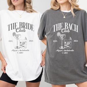 K&ouml;nnte beinhalten: Zwei wei&szlig;e T-Shirts mit einem Vintage-Grafikdesign. Der Text auf den Shirts lautet "The Bride Club" und "The Bach Club". Beide Shirts zeigen ein Cocktailglas und ein Glas mit Eisw&uuml;rfeln. Der Text "Est. 2024" und "Alyssa's Bachelorette Cabo" ist ebenfalls auf den Shirts enthalten.