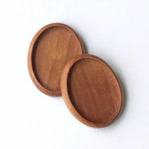 Peut inclure: Deux sous-verres ronds en bois de cerisier. Les sous-verres sont de forme ovale et ont une finition lisse et polie.