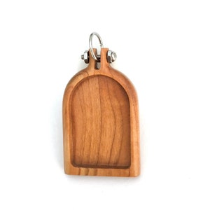 May include: A wooden embroidery hoop with a cherry wood finish. The hoop has a metal ring at the top for hanging. The hoop is 4 inches in diameter.