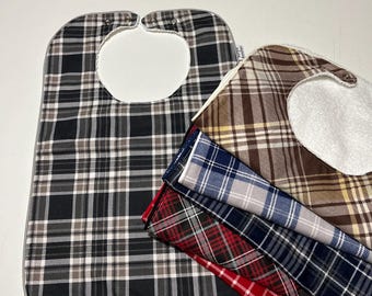 Könnte beinhalten: Ein Set aus fünf karierten Lätzchen in verschiedenen Farben, darunter Schwarz, Braun, Grau, Blau und Rot. Die Lätzchen sind aus einem weichen, saugfähigen Stoff gefertigt und haben ein Fleecefutter für zusätzlichen Komfort.