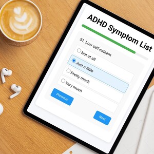 以下が含まれることがあります： ADHD症状リストというタイトルのアンケートが表示されたデジタルタブレット。自己肯定感の低さに関する質問があり、4つの選択肢があります。「全くない」「少し」「かなり」「非常に」。「少し」が選択されています。