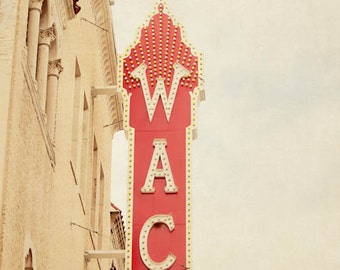 May include: A vintage red and white neon sign that reads "WACO" with a decorative top, mounted on a beige brick building. The sign is lit with small yellow lights. A green sign below reads "HIPPODROME".