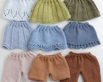 May include: A set of ten knitted doll clothes in various colors, including light blue, green, brown, and pink. The clothes are all different styles, including skirts, pants, and shorts.