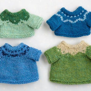 May include: Four knitted sweaters in different color combinations. The sweaters are green and blue, blue and green, green and beige, and blue and beige.