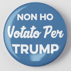 May include: A round, blue button with white text that reads "NON HO Votato Per TRUMP". The button is centered on a white background.