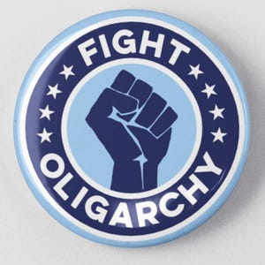 May include: A round, light blue button with the words "FIGHT OLIGARCHY" in white text. The button features a raised fist graphic in the center, surrounded by stars. The button is a political statement.
